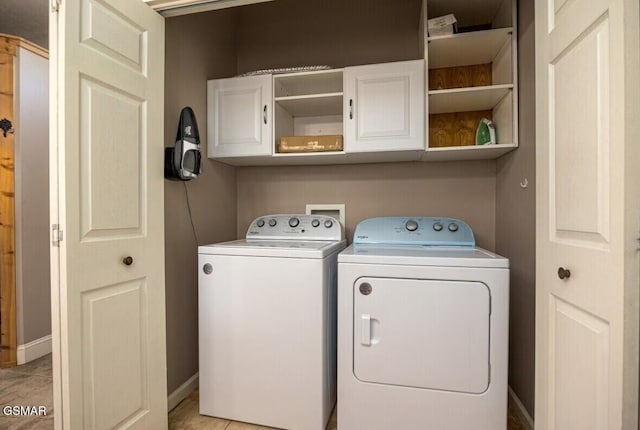 laundry room featuring cabinets, light tile patterned floors, and washer and dryer