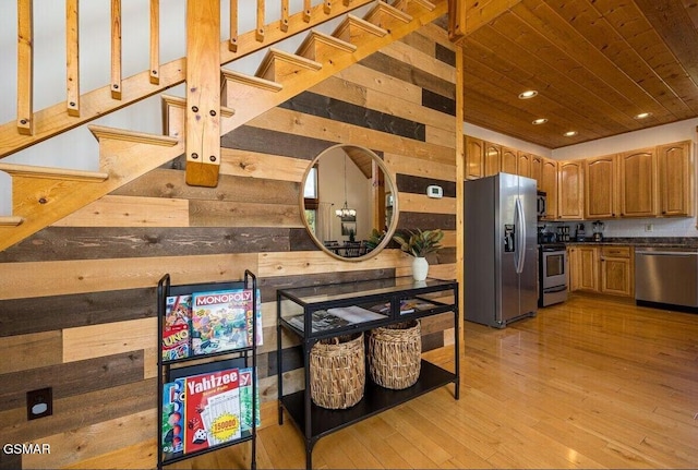 kitchen with wood ceiling, stainless steel appliances, wooden walls, and light wood-type flooring