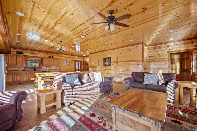 living room featuring sink, wooden walls, wood ceiling, ceiling fan with notable chandelier, and light wood-type flooring