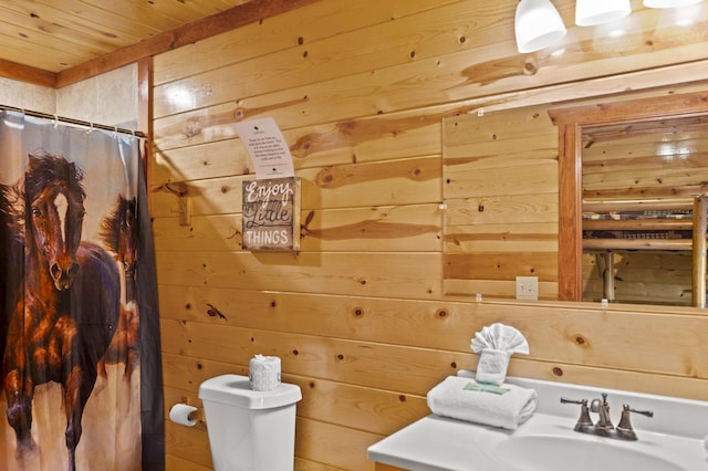 bathroom with curtained shower, sink, wood walls, toilet, and wood ceiling