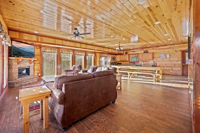 living room with a stone fireplace, wood walls, ceiling fan, and wood ceiling