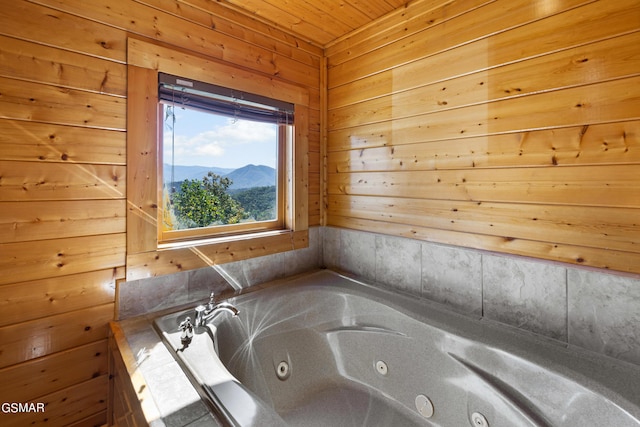 bathroom with wooden ceiling, a mountain view, wooden walls, and a tub to relax in