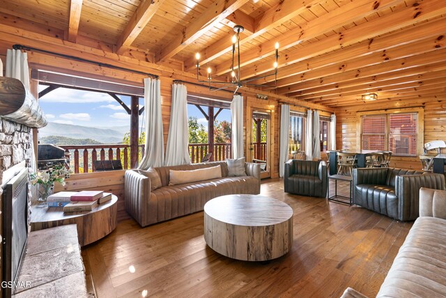 living room with hardwood / wood-style flooring, a stone fireplace, wooden ceiling, wooden walls, and beamed ceiling