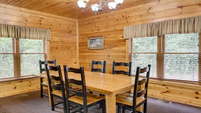 dining room featuring carpet flooring, wood ceiling, wooden walls, and a chandelier