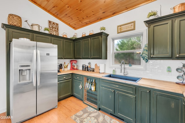 kitchen with butcher block counters, sink, green cabinetry, and stainless steel refrigerator with ice dispenser