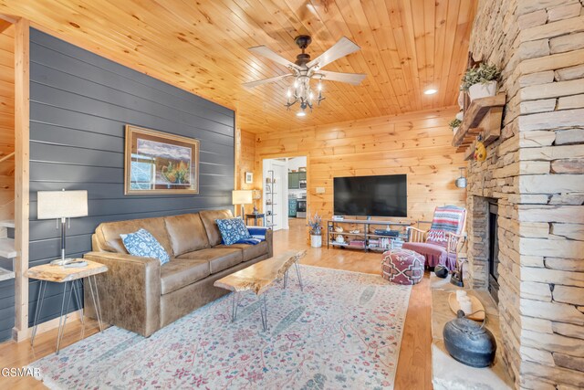 living room with wood-type flooring, ceiling fan, a fireplace, and wood ceiling