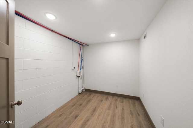 below grade area with light wood finished floors, recessed lighting, visible vents, and baseboards