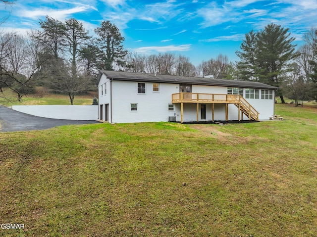 rear view of property featuring stairs, driveway, a yard, and a wooden deck