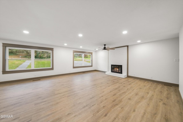 unfurnished living room with ceiling fan, recessed lighting, baseboards, light wood-style floors, and a brick fireplace