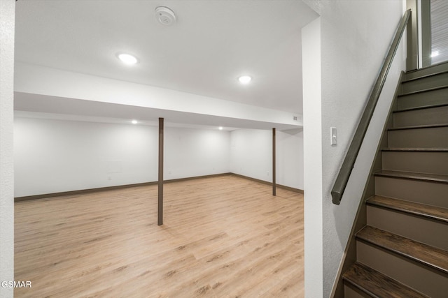 finished below grade area with stairs, light wood finished floors, recessed lighting, and baseboards