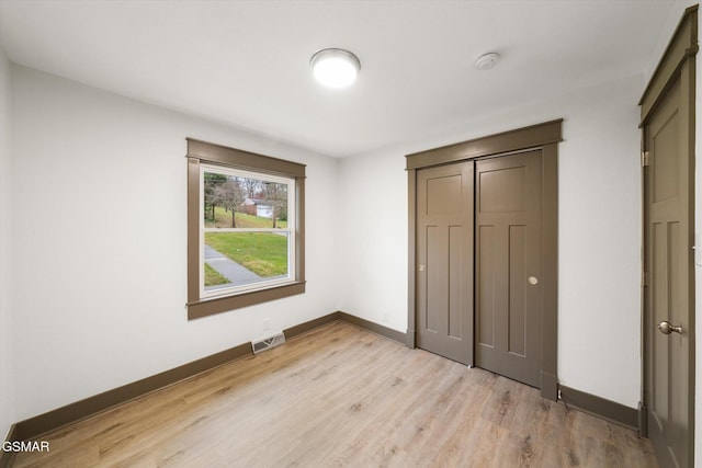 unfurnished bedroom with a closet, baseboards, visible vents, and light wood finished floors