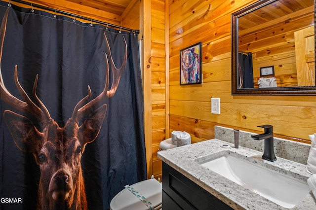 bathroom featuring toilet, vanity, wood walls, and a shower with shower curtain