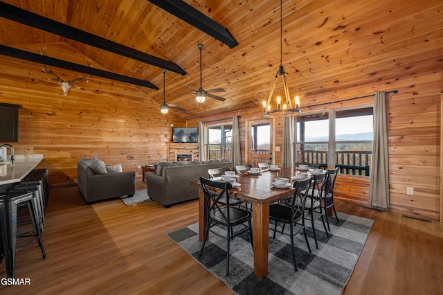 dining space featuring ceiling fan with notable chandelier, hardwood / wood-style floors, beamed ceiling, high vaulted ceiling, and wooden ceiling