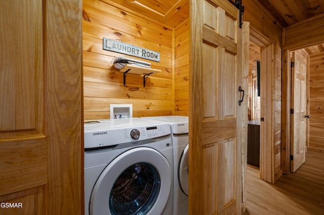 washroom featuring wood ceiling, washer and clothes dryer, a barn door, and wooden walls