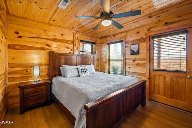 bedroom with ceiling fan, wood ceiling, hardwood / wood-style flooring, and wooden walls