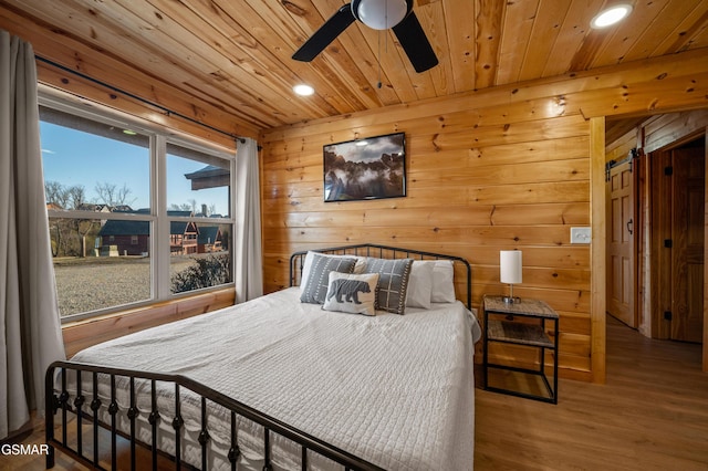 bedroom with ceiling fan, hardwood / wood-style floors, wood walls, and wood ceiling