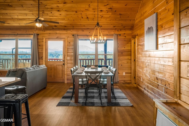 dining area with lofted ceiling, dark wood-type flooring, and wood walls