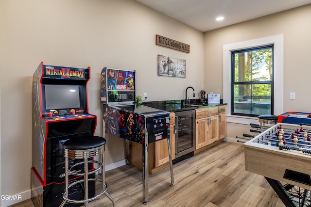 bar with light brown cabinets, light wood-type flooring, sink, and beverage cooler