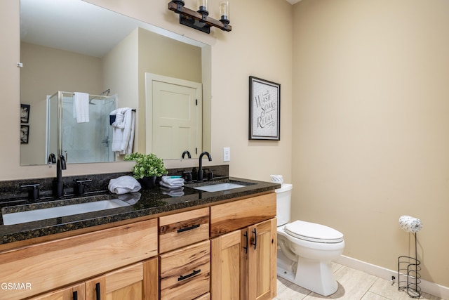 bathroom with tile patterned floors, vanity, toilet, and a shower with door