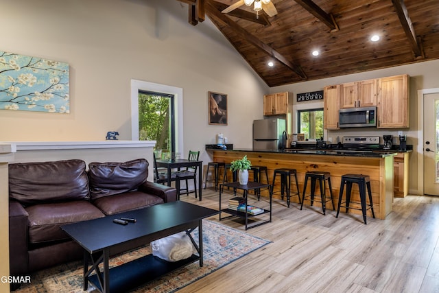 living room featuring beam ceiling, light hardwood / wood-style flooring, and high vaulted ceiling