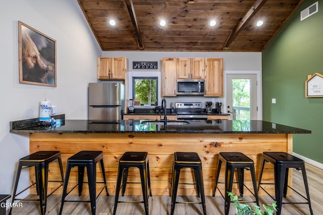 kitchen with sink, light brown cabinets, stainless steel appliances, light hardwood / wood-style flooring, and a breakfast bar