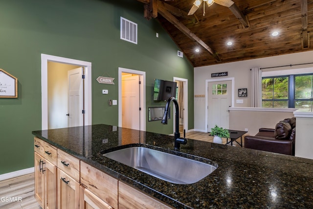 kitchen with sink, dark stone countertops, light brown cabinetry, beamed ceiling, and wood ceiling