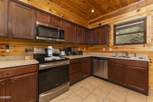 kitchen featuring sink, wooden ceiling, wooden walls, light tile patterned floors, and appliances with stainless steel finishes