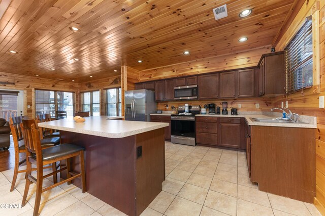 kitchen featuring wooden walls, a kitchen island, sink, and appliances with stainless steel finishes