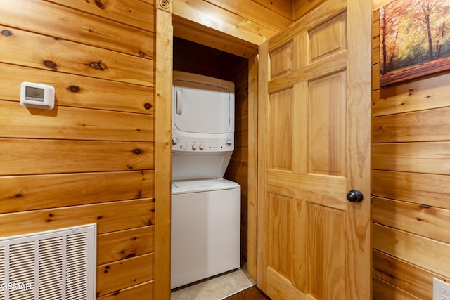 laundry room featuring stacked washing maching and dryer and wood walls