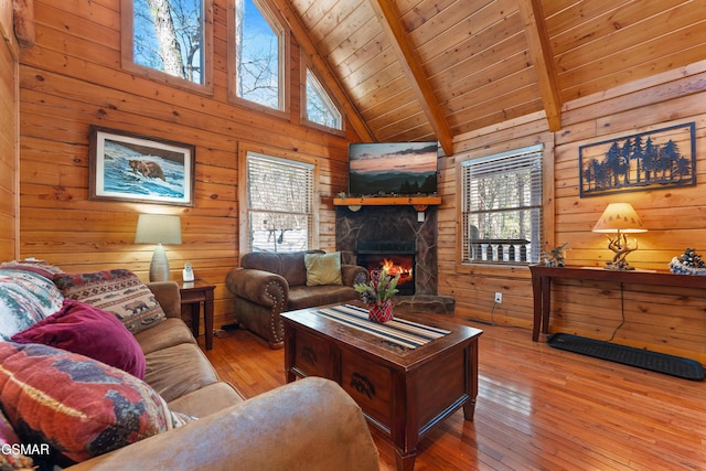 living room featuring beamed ceiling, wooden ceiling, a wealth of natural light, and wooden walls