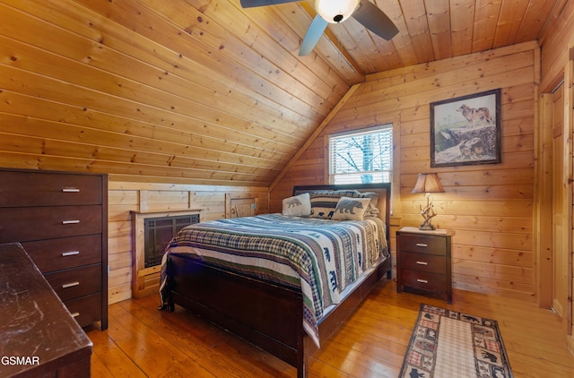 bedroom featuring lofted ceiling, hardwood / wood-style floors, and wood walls