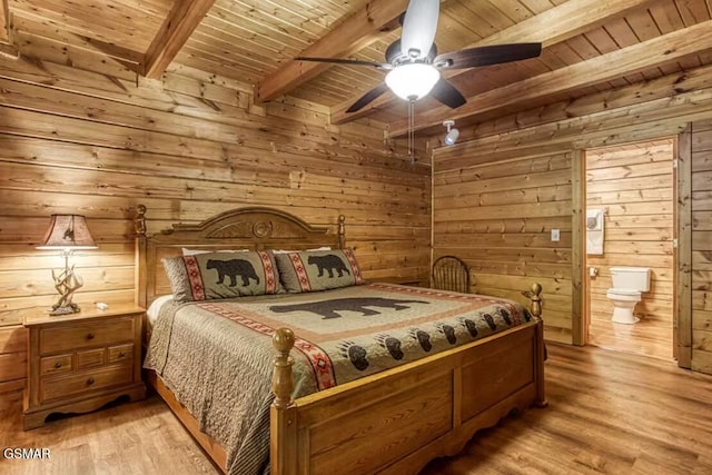 bedroom featuring ceiling fan, light hardwood / wood-style floors, beam ceiling, ensuite bath, and wooden ceiling