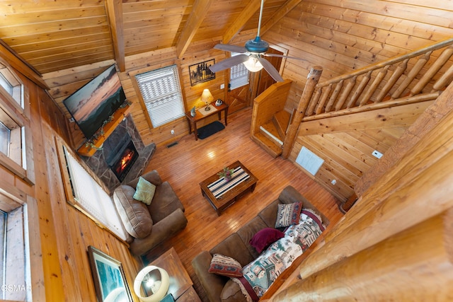 living area featuring wooden ceiling, wood walls, a fireplace, high vaulted ceiling, and beam ceiling