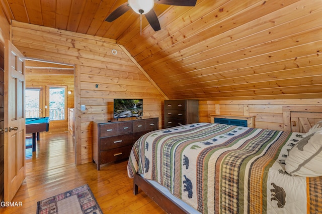 bedroom featuring lofted ceiling, light wood finished floors, wood ceiling, and wooden walls