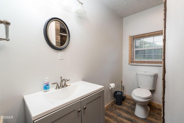 bathroom with hardwood / wood-style floors, vanity, a textured ceiling, and toilet