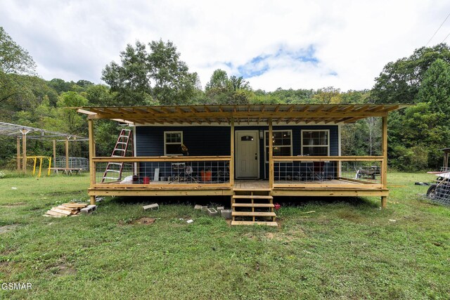 view of front facade with a front yard, a pergola, and a deck