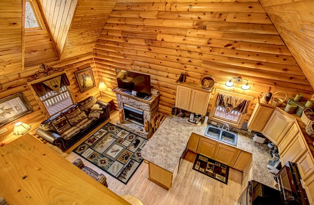 living room featuring rustic walls, sink, a stone fireplace, high vaulted ceiling, and light hardwood / wood-style floors