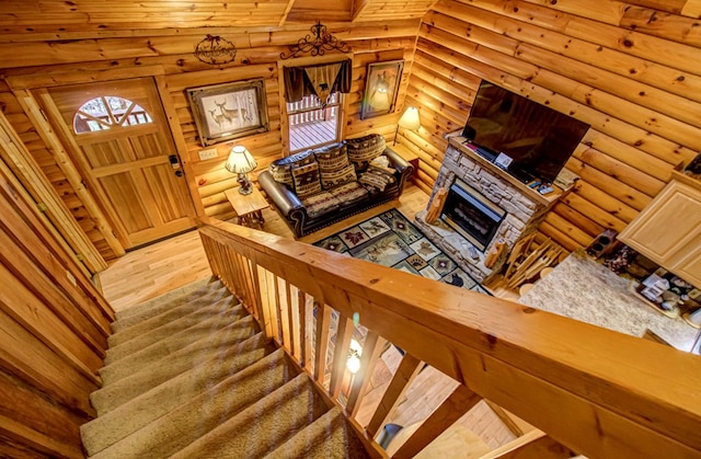 living room featuring a stone fireplace, log walls, and light hardwood / wood-style floors