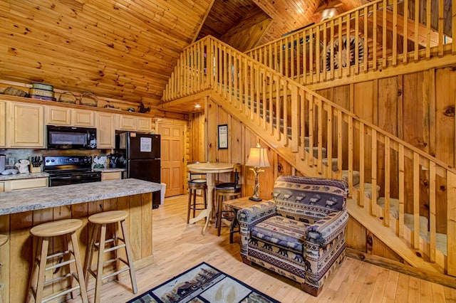 kitchen with wooden ceiling, light hardwood / wood-style flooring, black appliances, and wooden walls