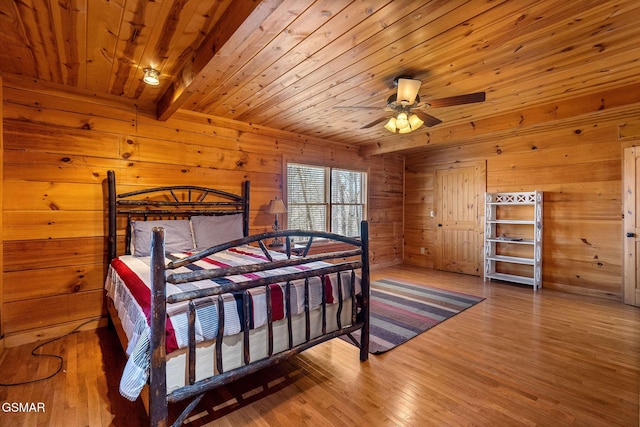 bedroom with wooden ceiling, beamed ceiling, wooden walls, and wood finished floors