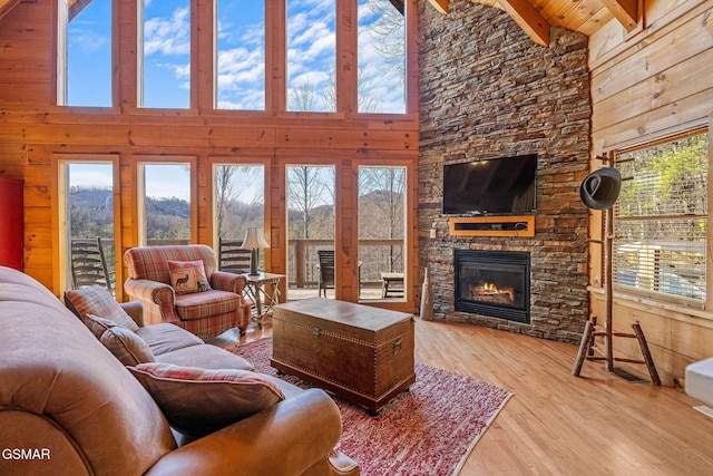 living room with a fireplace, wood walls, lofted ceiling with beams, and wood finished floors