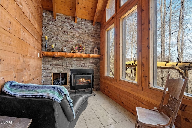 interior space featuring light tile patterned floors, wood walls, a fireplace, wood ceiling, and beam ceiling