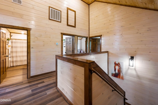 hall featuring hardwood / wood-style flooring, high vaulted ceiling, and wood walls