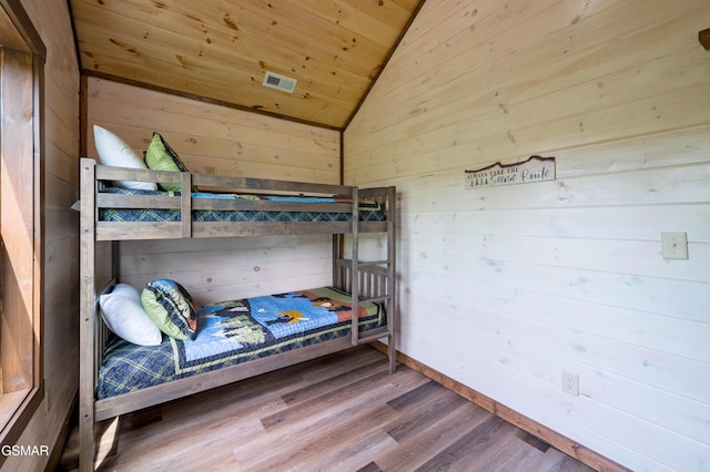 unfurnished bedroom featuring lofted ceiling, hardwood / wood-style floors, wooden ceiling, and wood walls