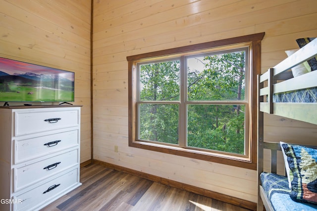 unfurnished bedroom with multiple windows, hardwood / wood-style flooring, and wood walls