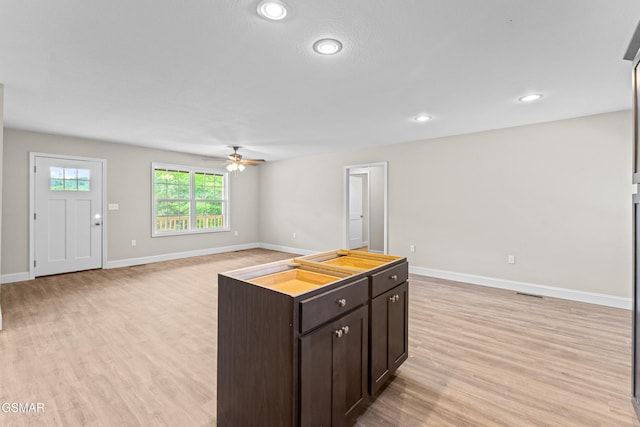 kitchen featuring a ceiling fan, light wood-type flooring, dark brown cabinets, baseboards, and open floor plan