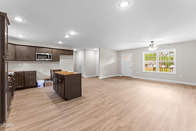 kitchen with stainless steel microwave, dark brown cabinets, light wood-style flooring, baseboards, and recessed lighting