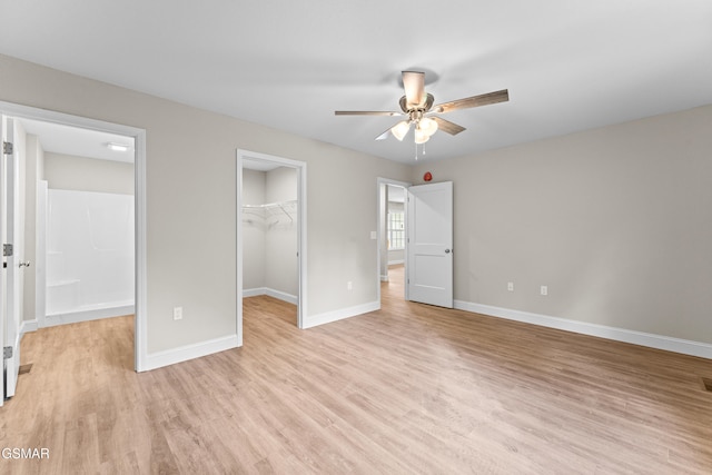 unfurnished bedroom with light wood finished floors, a spacious closet, baseboards, and a closet