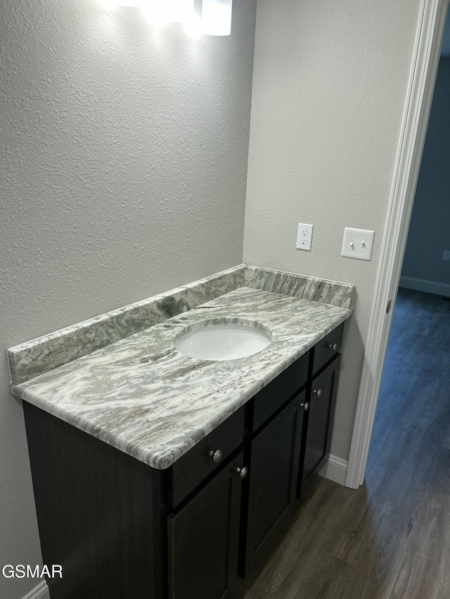 bathroom with wood finished floors, vanity, and baseboards