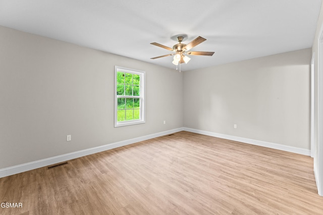 spare room with light wood finished floors, a ceiling fan, and baseboards